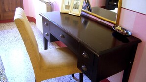 Ein dunkler Holztisch mit Schubladen und einem Spiegel, ein gerahmtes Bild und eine kleine Schale darauf.