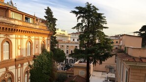 A historic building with ornate architecture, a courtyard with trees, and adjacent residential buildings. - GH Casa Vicenza (Rome)