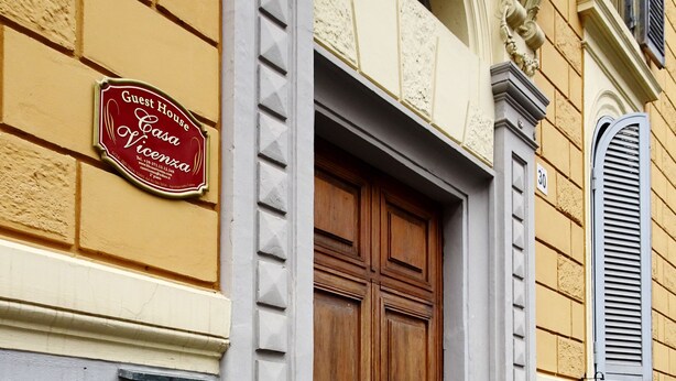A building with a large wooden door, a brass doorbell, and a sign that reads "Guest House Casa Vicenca." - GH Casa Vicenza (Rome)