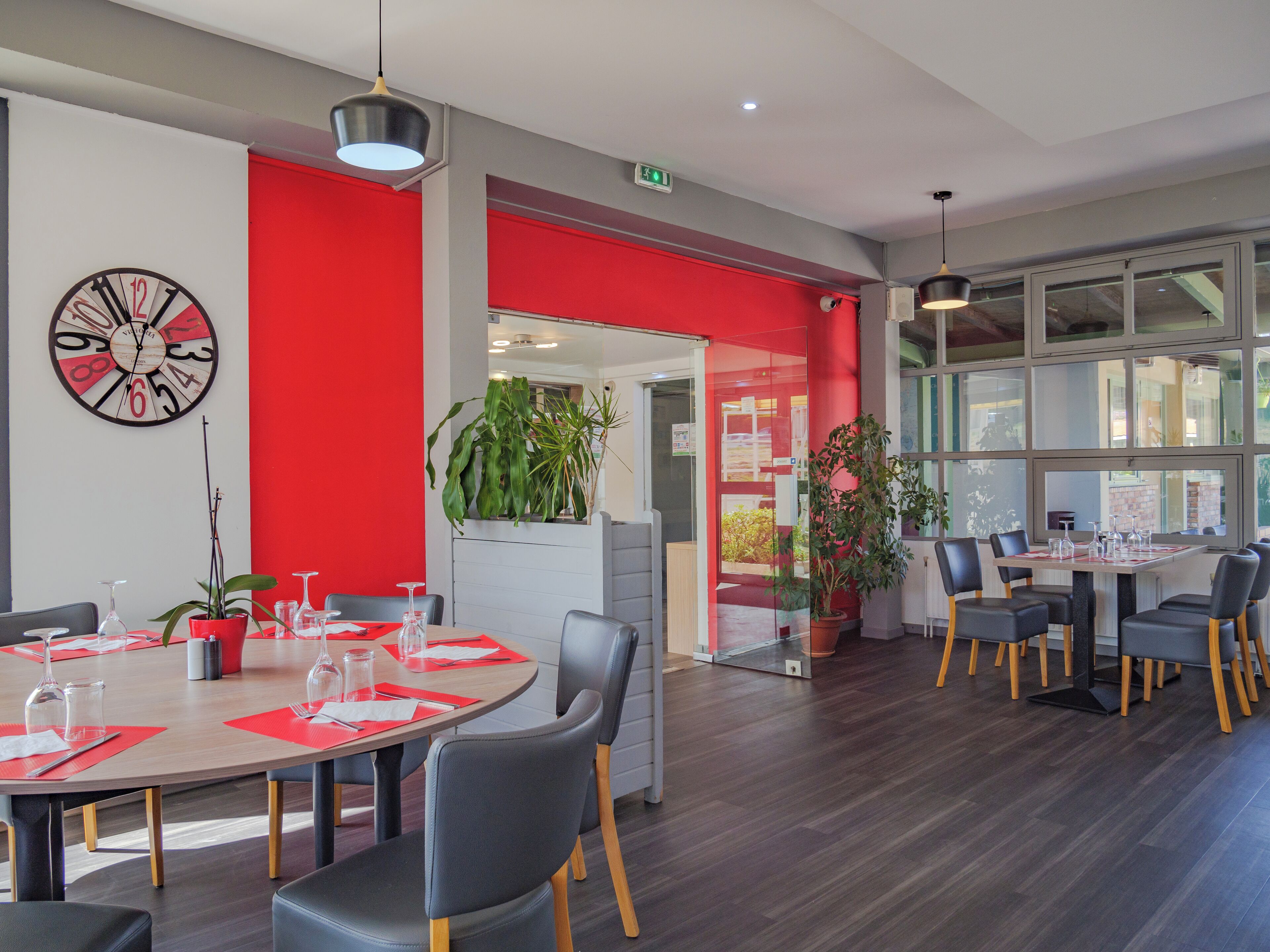 A modern dining area with a round table, chairs, and potted plants.