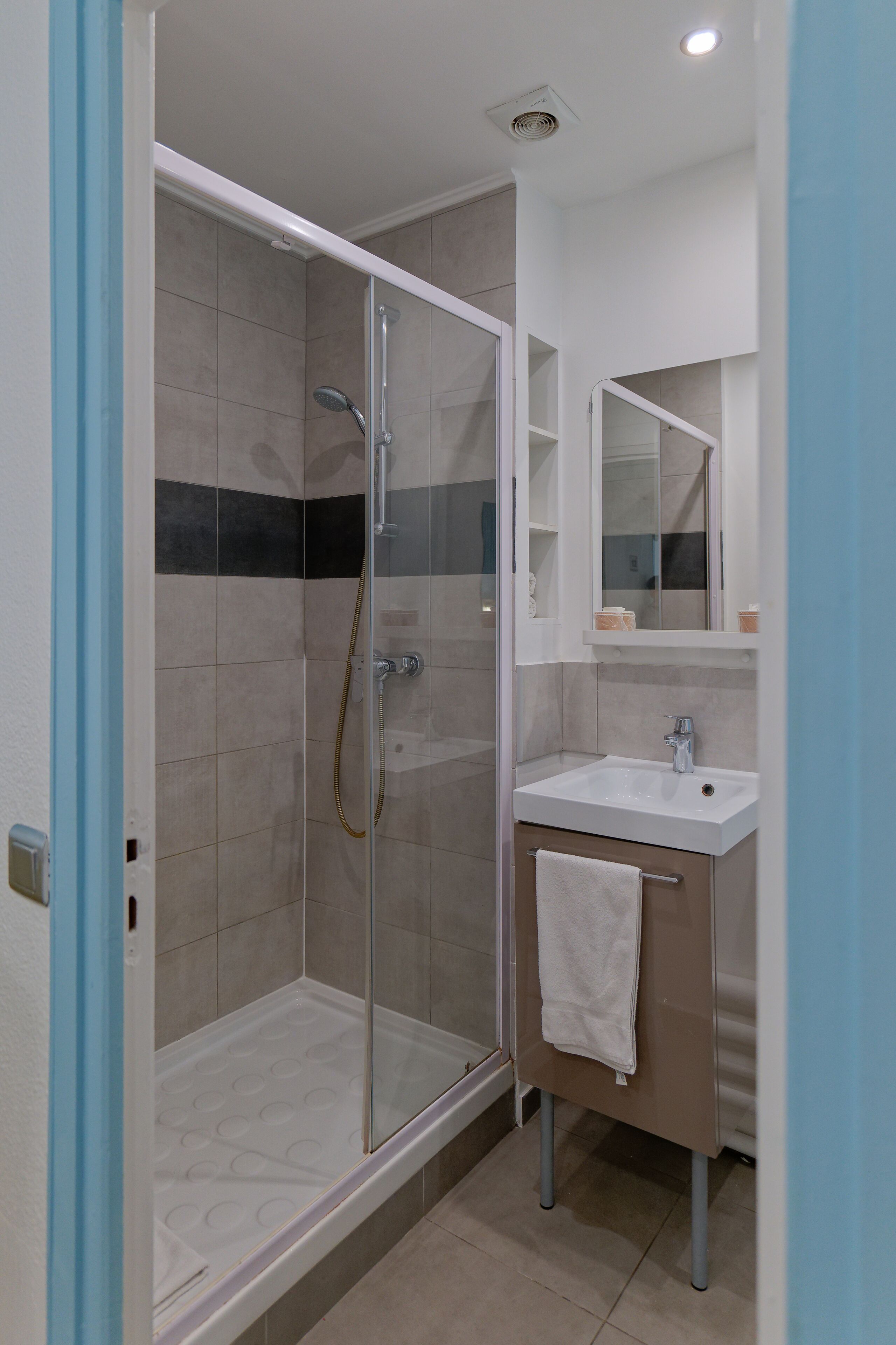 A modern bathroom with a glass-enclosed shower, a white sink, and a mirror above the sink.
