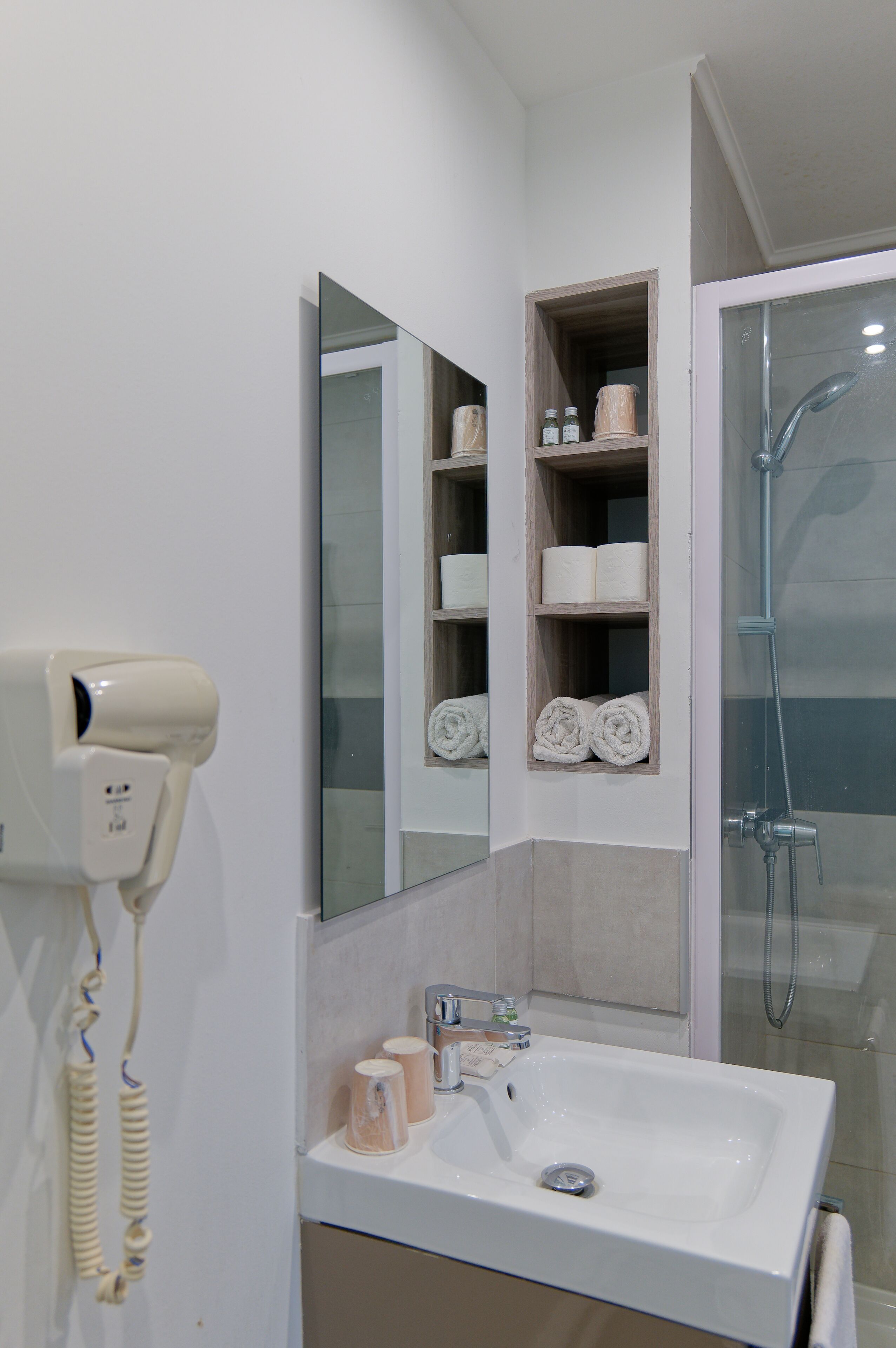 A bathroom with a white sink, mirror, and shelves with towels.