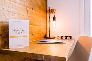 A wooden desk with a framed sign, a lamp, and a chair.