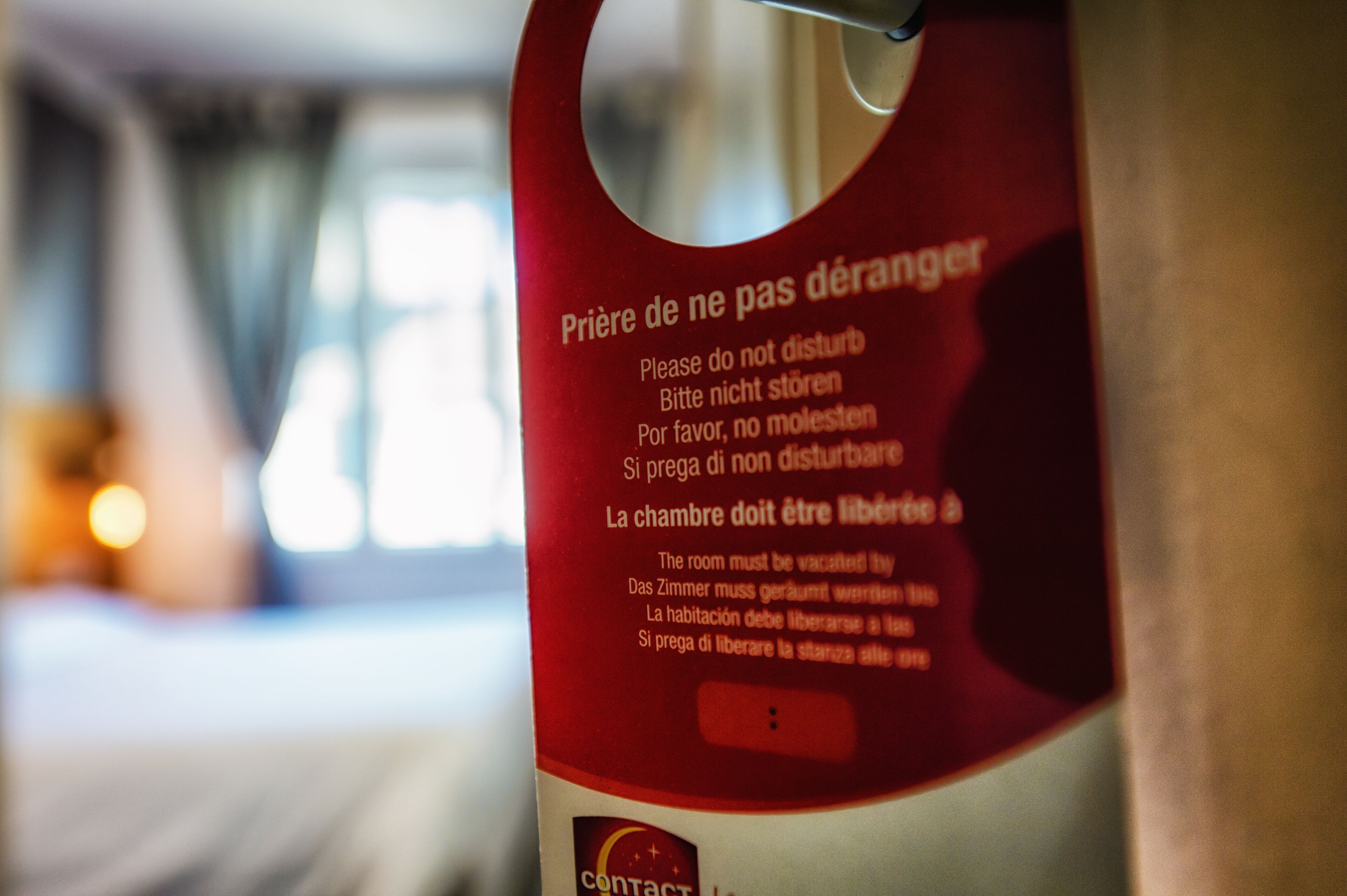 A close-up of a red sign with multilingual instructions for a hotel room.