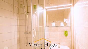 A modern bathroom with a glass-enclosed shower, a white sink, and a mirror above the sink.