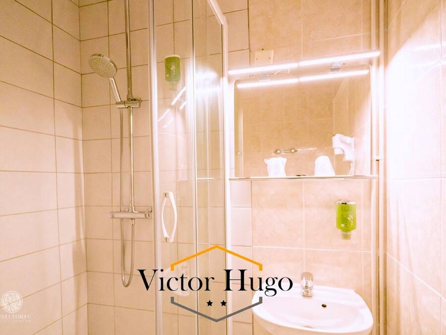 Un baño moderno con ducha envuelta en vidrio, un lavabo blanco y un espejo sobre él.
