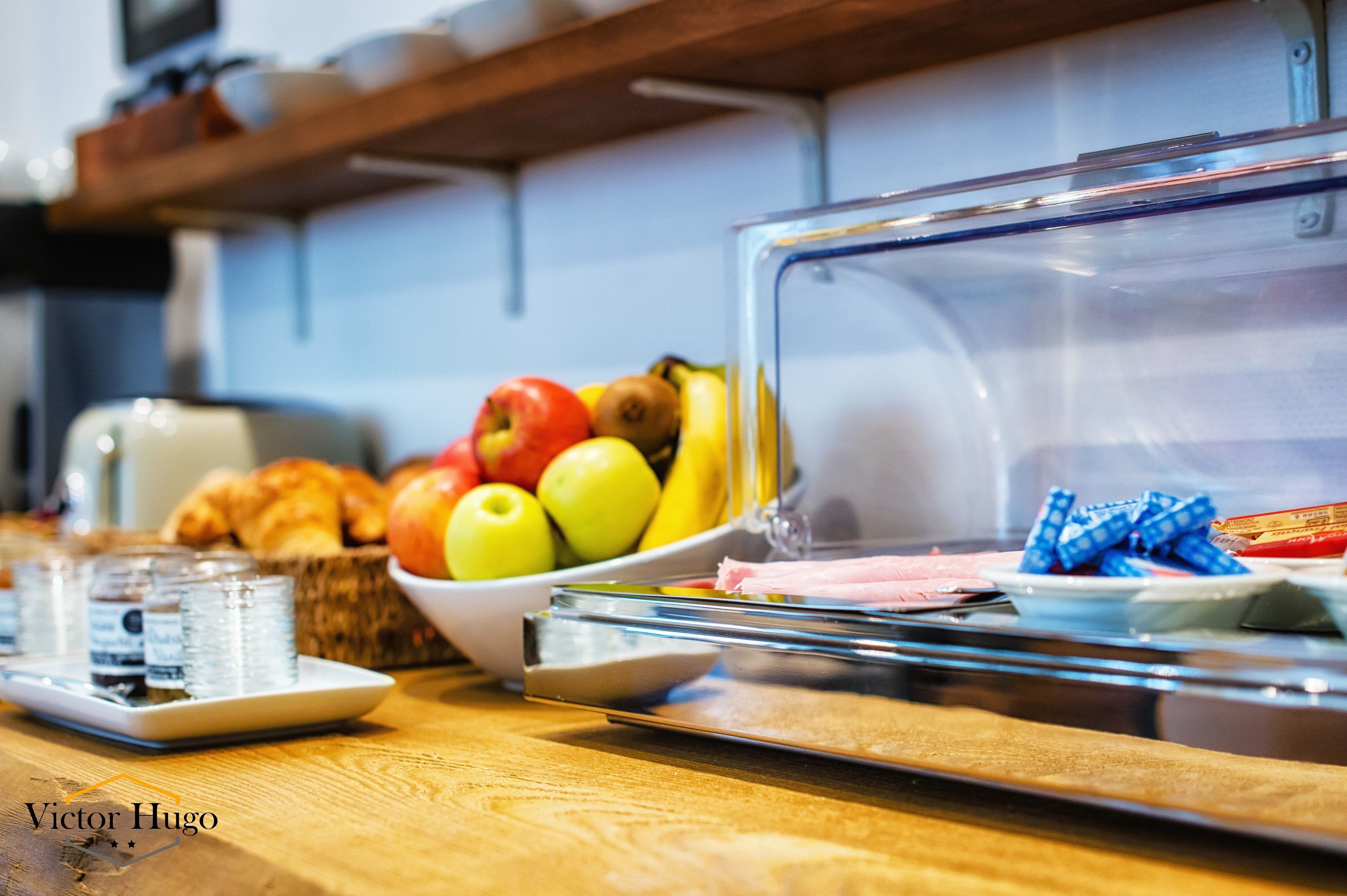 A breakfast buffet with fruits, pastries, and bottled water.