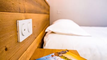Una testiera in legno con un interruttore, un cuscino bianco e una rivista su un comodino di legno.