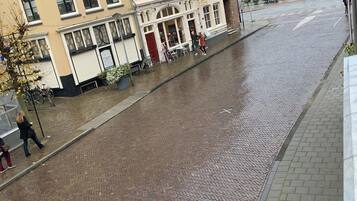 Een straat met cobblestones, met een gebouw met meerdere ramen en een rode deur.