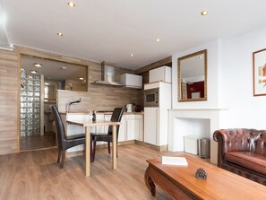 A modern living room with a dining area, a kitchen, and a fireplace. - Hotel de Vischpoorte (Deventer)