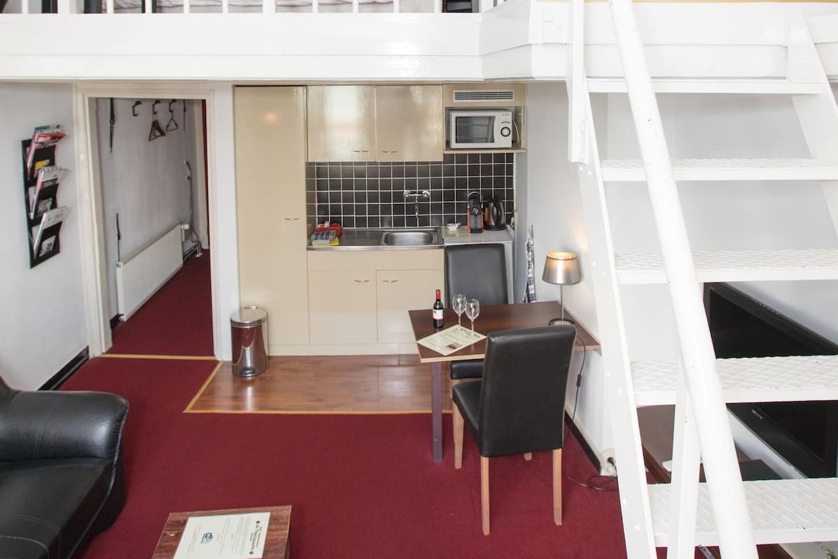 Un appartement de style « loft » comprenant une cuisine, un coin repas et un escalier menant à un niveau supérieur.