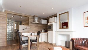 A modern kitchen with a dining area, a fireplace, and a leather sofa. - Hotel de Vischpoorte (Deventer)
