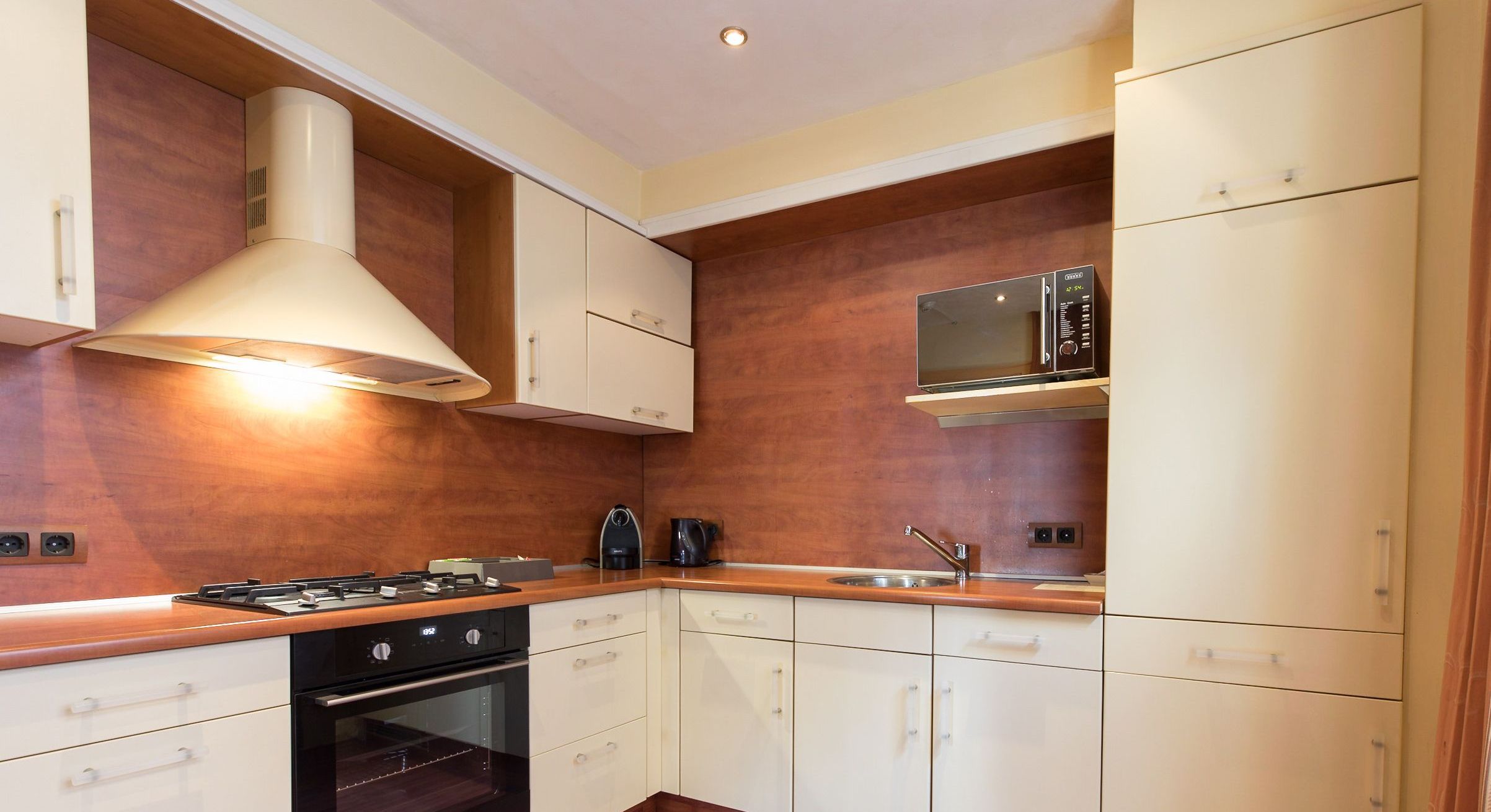 Una cocina moderna con armarios de madera, estufa a gas, horno, microondas y cafetera.