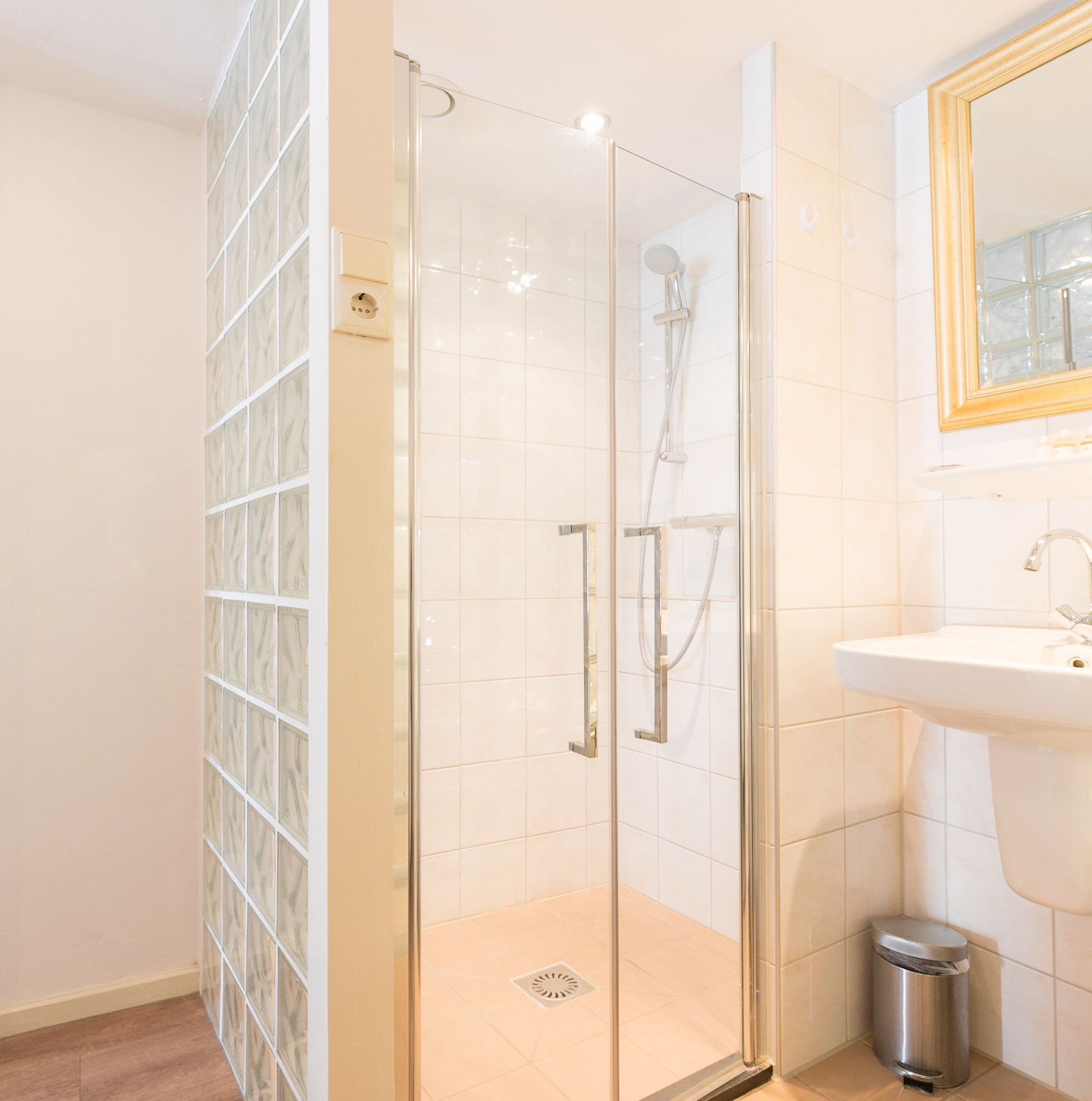 A modern bathroom with a glass-enclosed shower, a sink, and a mirror.