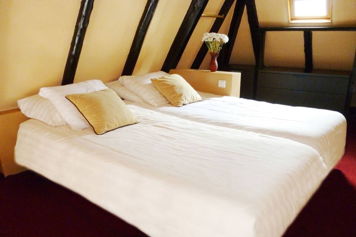 Une chambre avec deux lits, un vase de fleurs et une fenêtre.