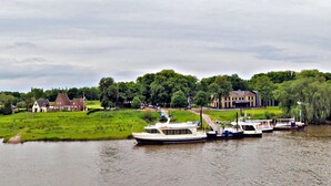 A river with boats, a bridge, and houses in a rural setting. - Hotel de Vischpoorte (Deventer)