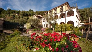 A two-story building with multiple balconies, surrounded by lush gardens and trees. - Villa Pane Resort (Sorrento)
