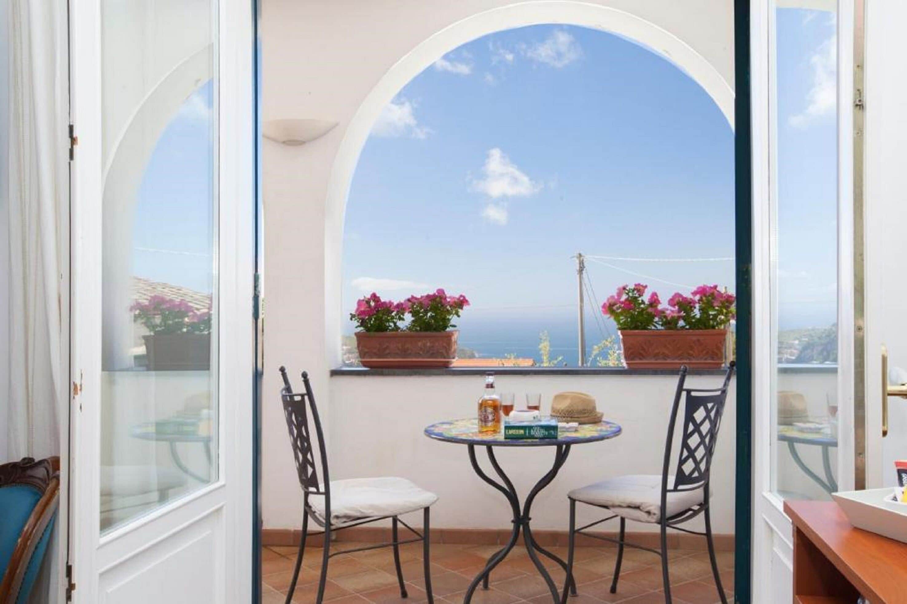 Ein Balkon mit zwei Stühlen, einem kleinen runden Tisch und Topfpflanzen.