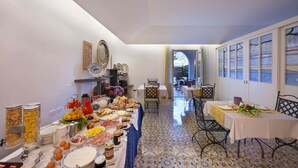 A dining area with a long table set for a meal, featuring various food items and condiments. - Villa Pane Resort (Sorrento)