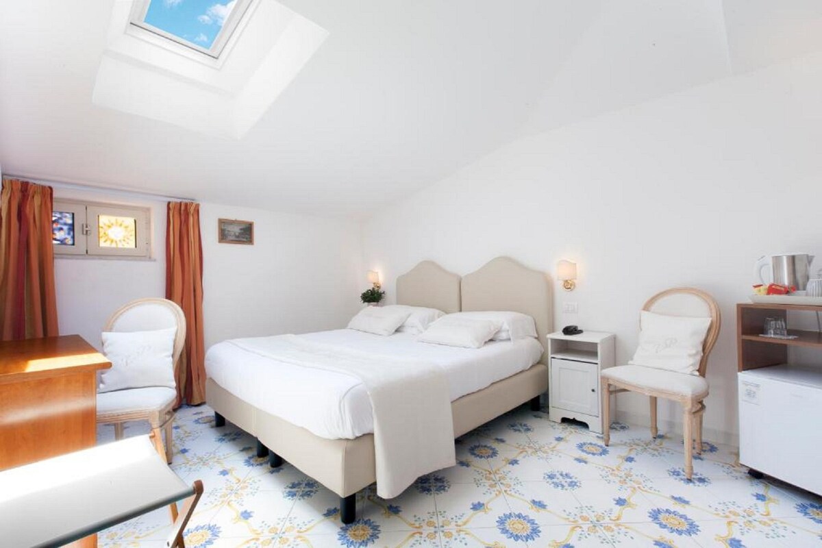 Una camera da letto con un letto, comodini, una sedia, una scrivania e un piccolo armadietto.