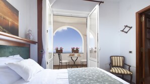 A bedroom with a bed, a chair, a table, and a balcony with a view. - Villa Pane Resort (Sorrento)