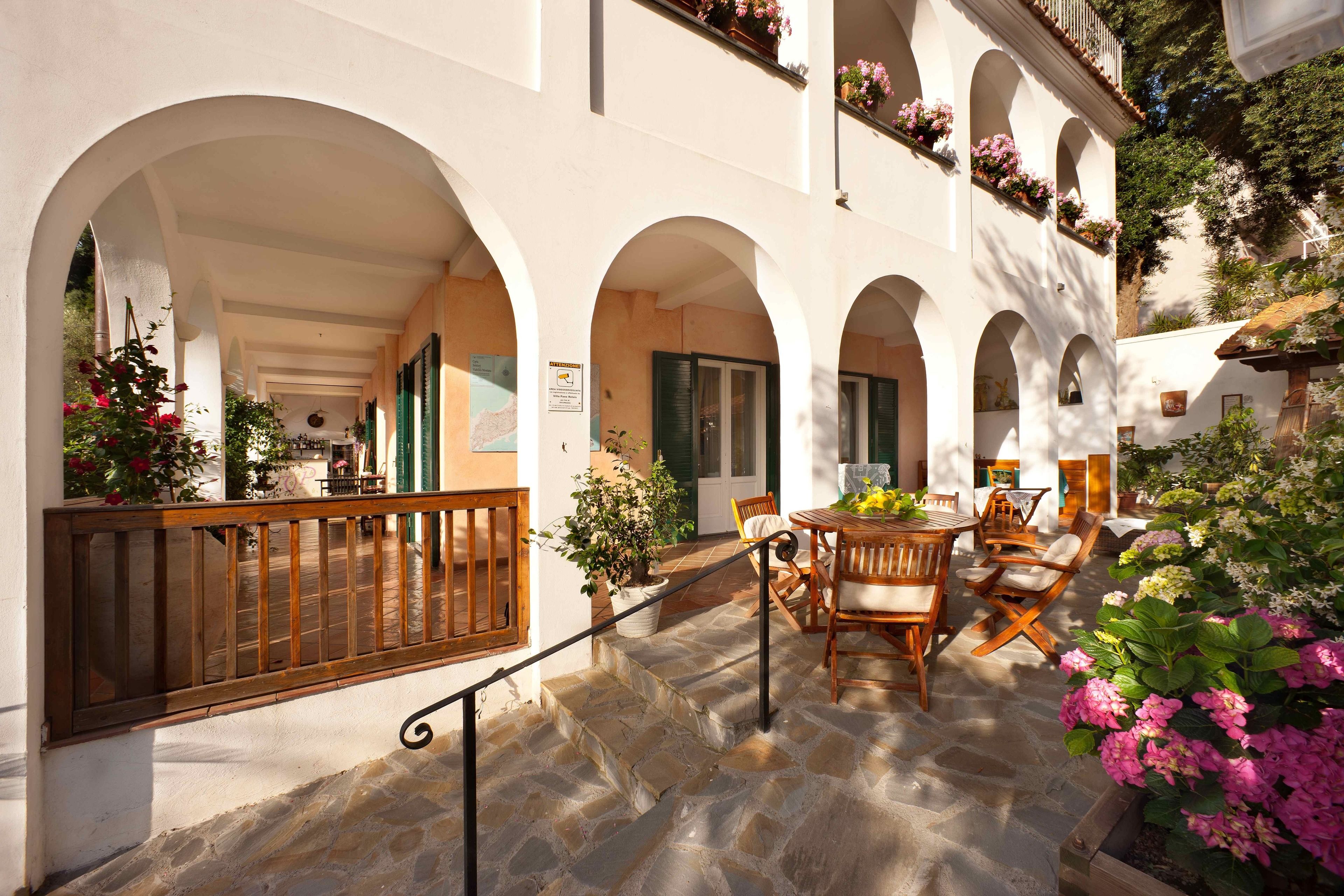 A courtyard with stone flooring, wooden furniture, and potted plants.