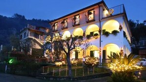 A two-story building with arched windows and balconies, surrounded by trees and illuminated by warm lights. - Villa Pane Resort (Sorrento)
