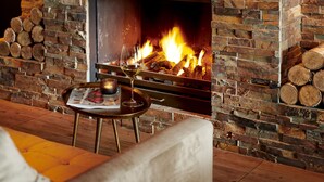 A cozy room with a fireplace, a round table with a glass of wine, and a magazine.