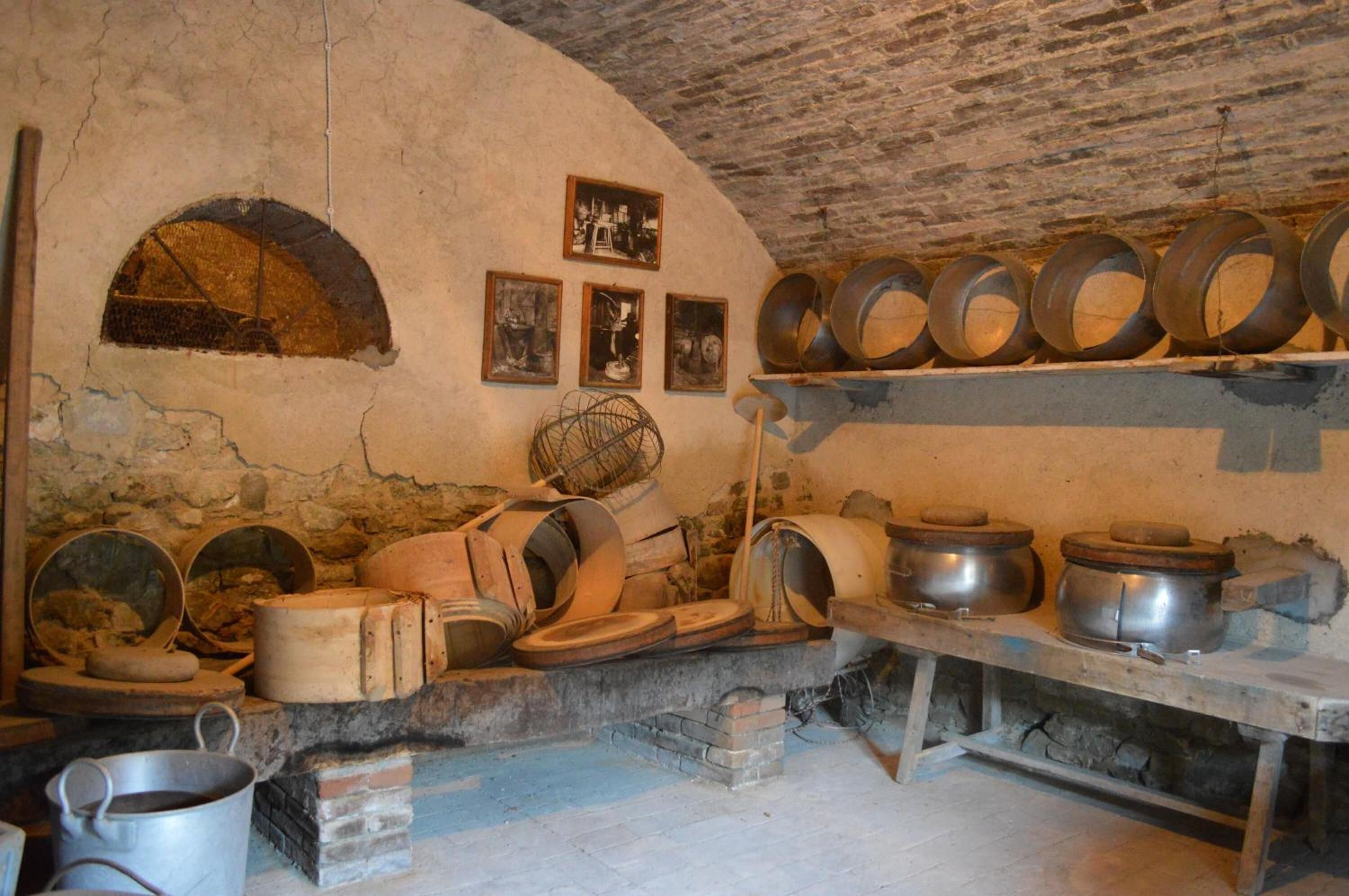 A rustic kitchen with stone walls, a brick oven, and various cooking utensils.