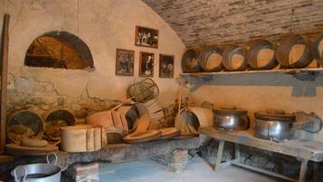 A rustic kitchen with stone walls, a brick oven, and various cooking utensils.
