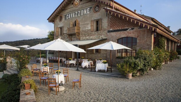 A building labeled "CAVAZZONE" with outdoor seating and umbrellas. - Cavazzone (Viano)