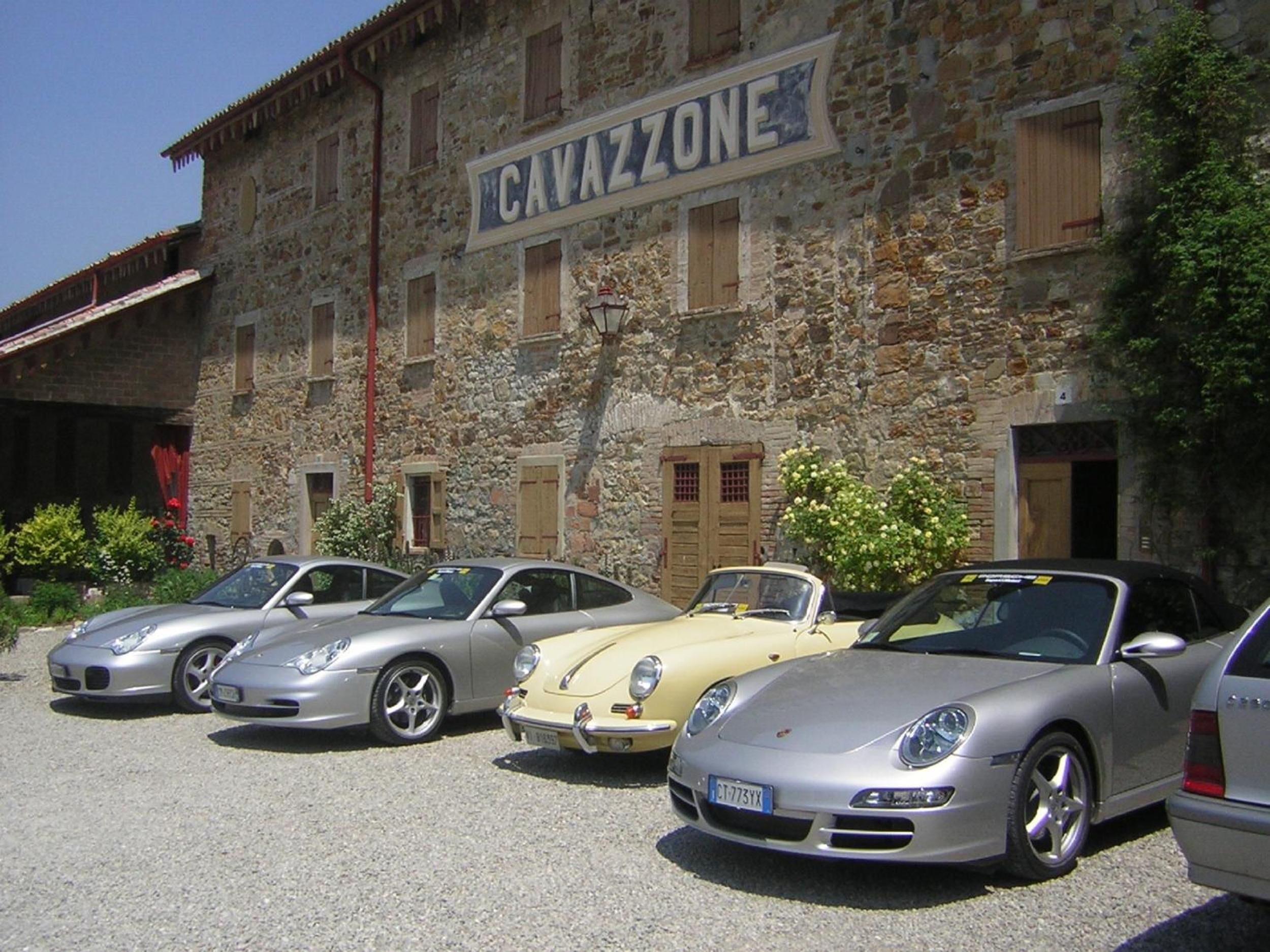 Une rangée de voitures garées devant un bâtiment en pierre, sur lequel on peut lire l’inscription « CAVAZZONE ».