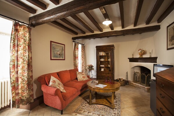 A cozy living room with a red sofa, a wooden coffee table, a fireplace, and a bookshelf.