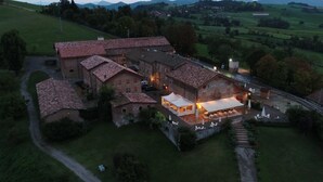 An aerial view of a historic building with a courtyard, a covered outdoor seating area, and a sign reading "CAVAZZONE". - Cavazzone (Viano)