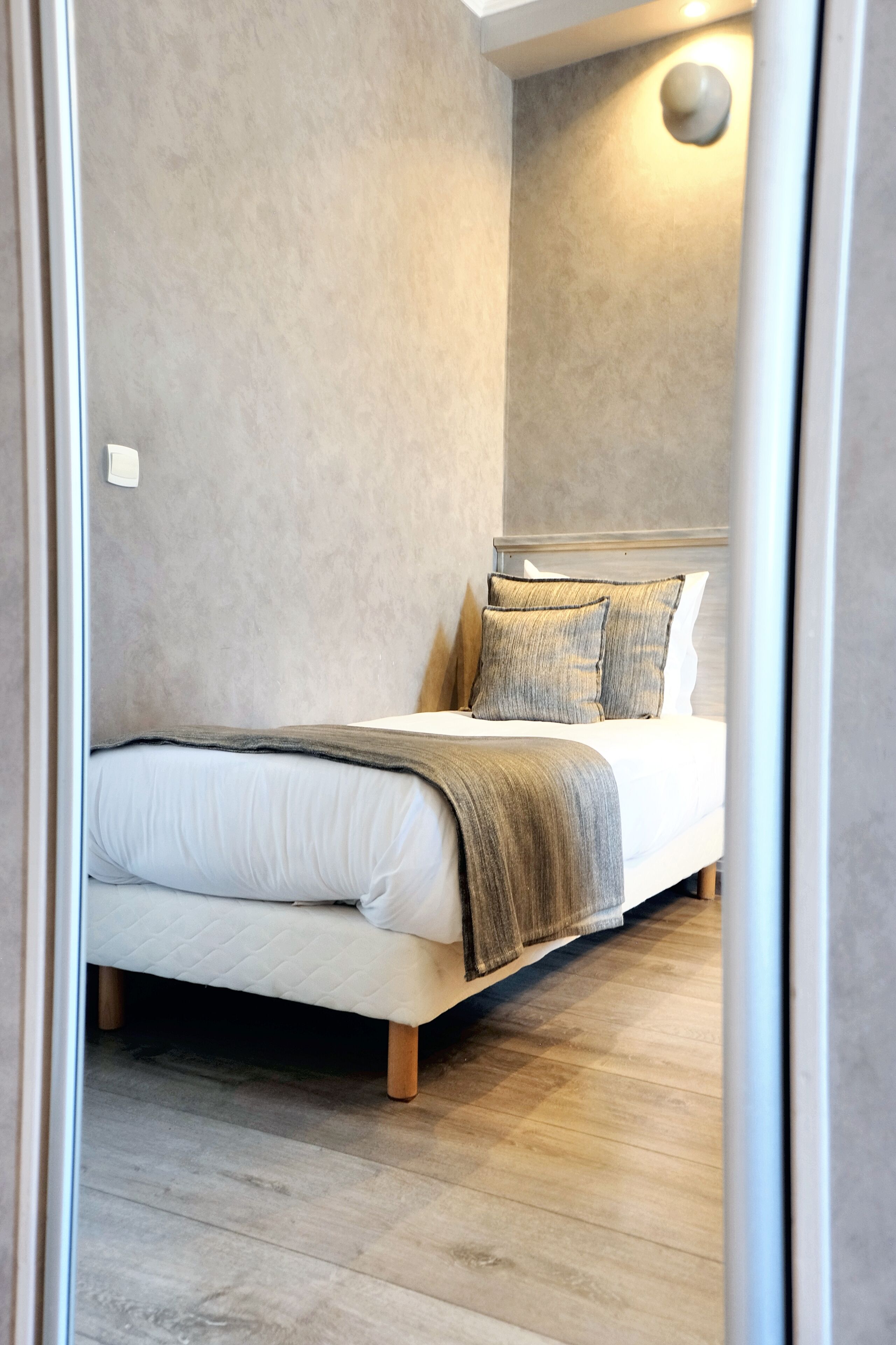 A bedroom with a bed, a headboard, and a wall-mounted light fixture.