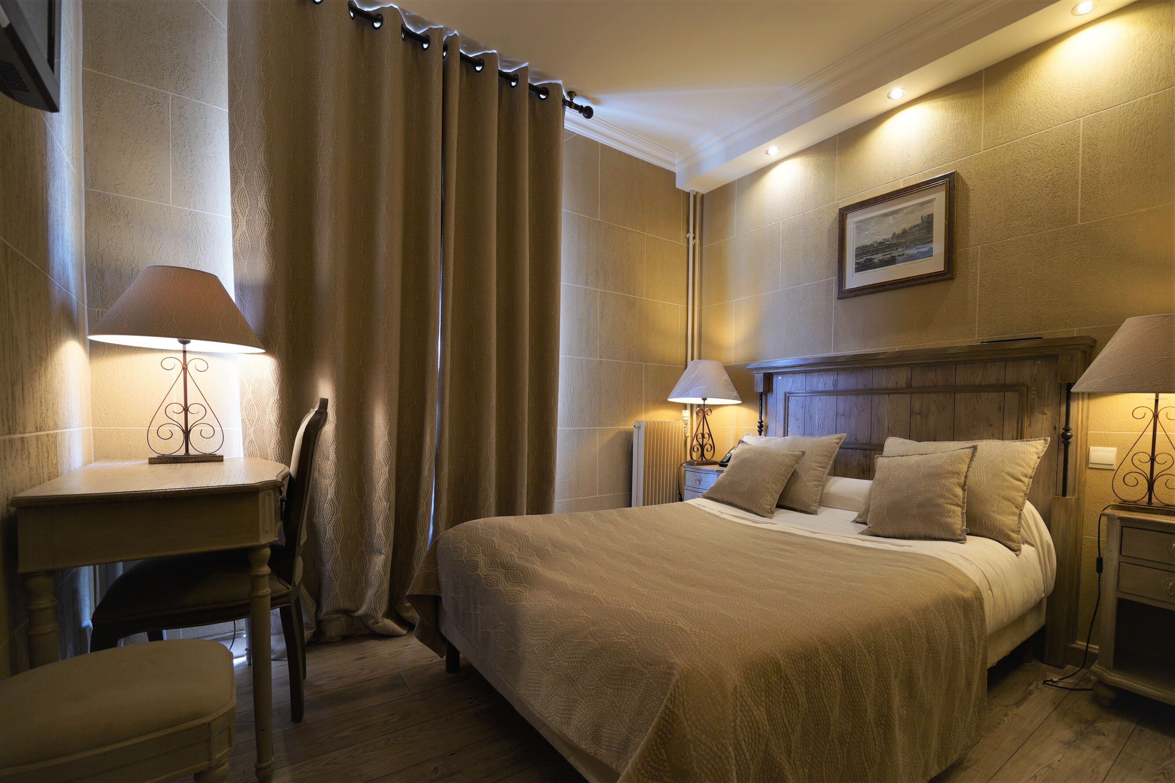 Une chambre d’hôtel avec un grand lit, deux tables de chevet avec des lampes, une chaise et un bureau.