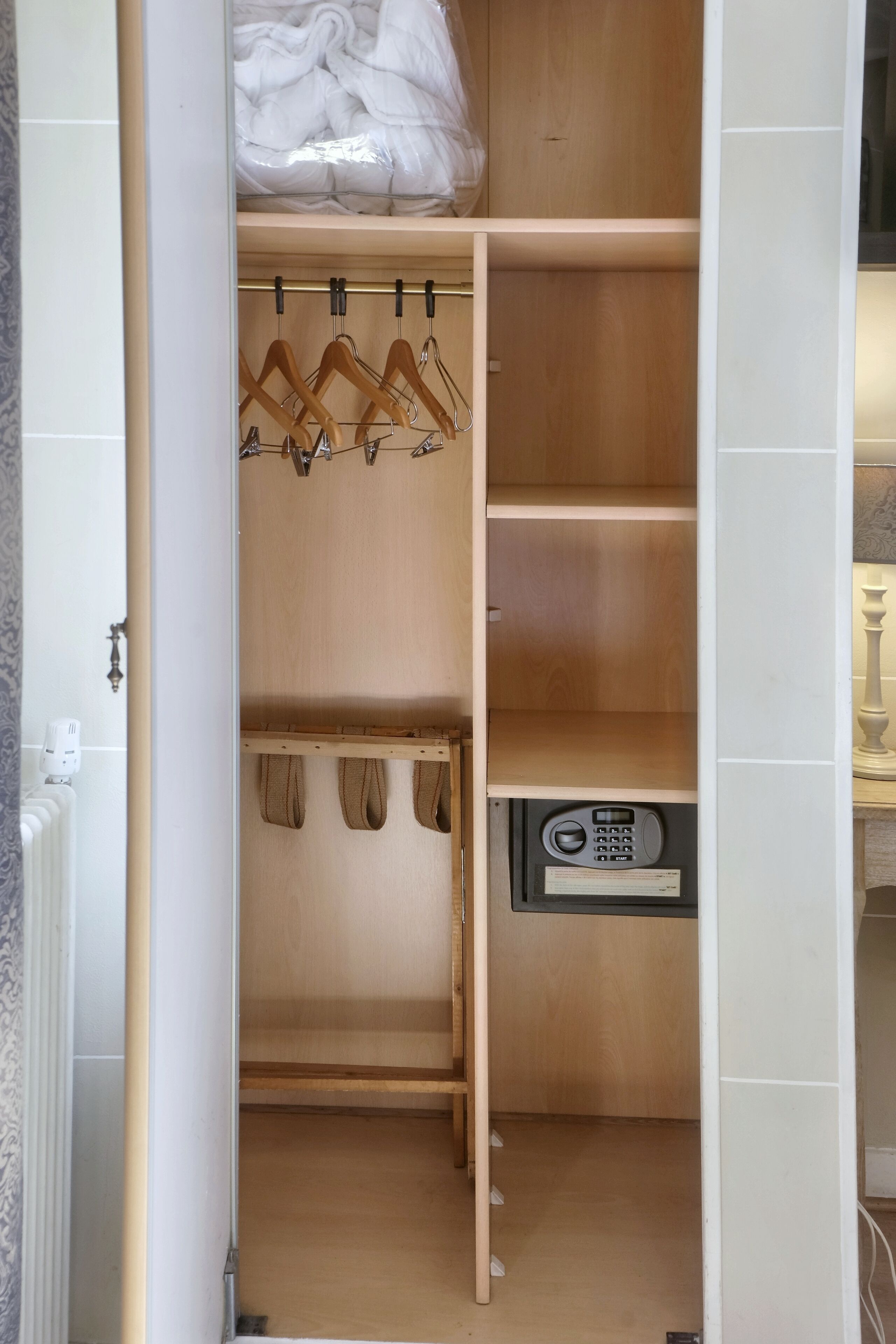 A wooden closet with hanging space, shelves, and a built-in safe.