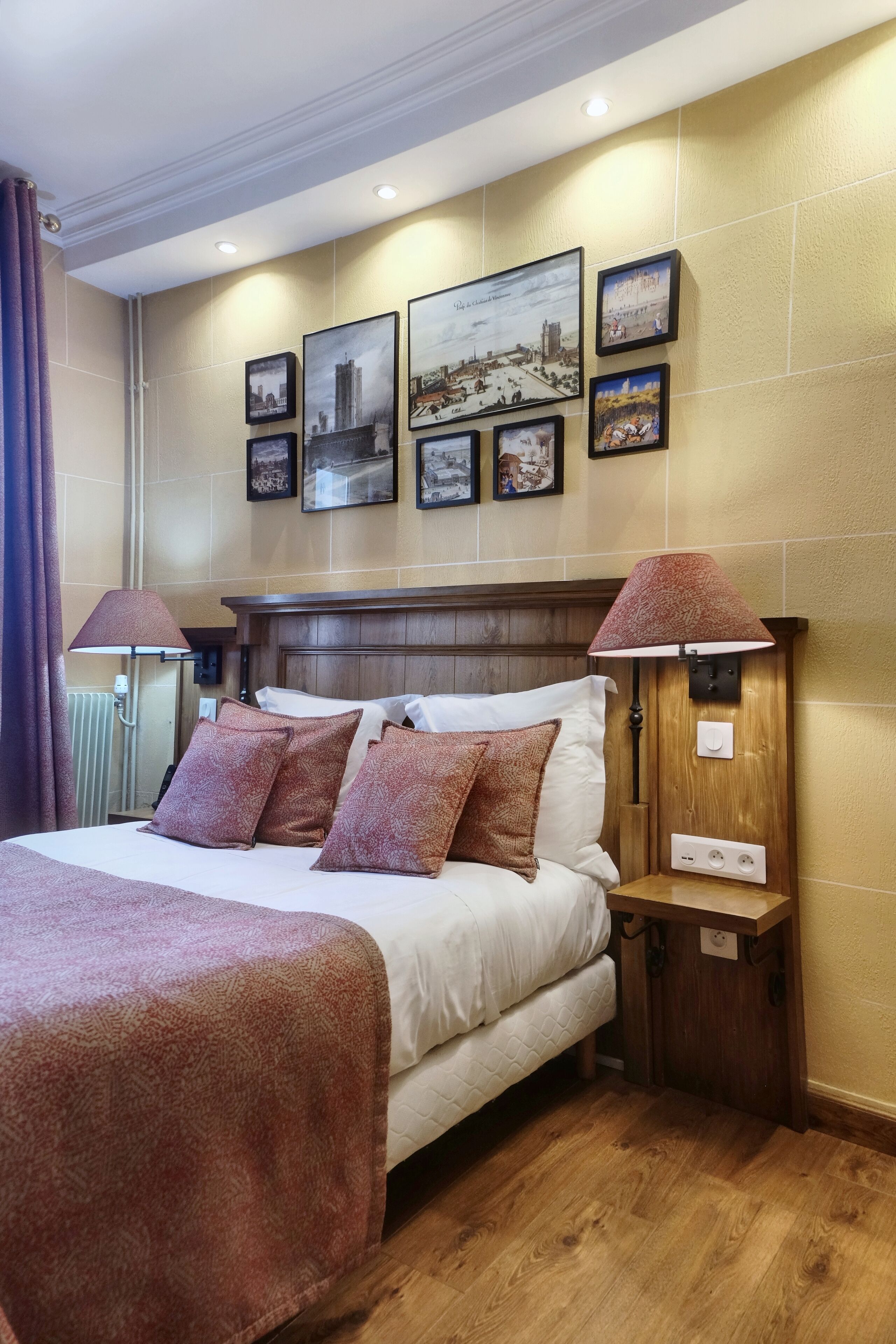 A hotel room with a large bed, two bedside tables, a headboard, and a wall with framed pictures.