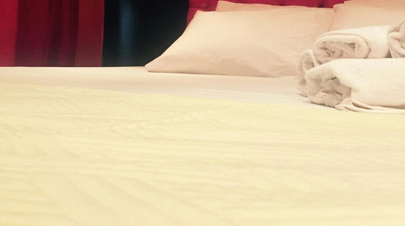 A neatly made bed with white linens and a folded towel on the side.