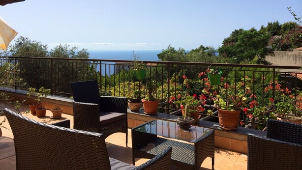 A balcony with wicker furniture, potted plants, and a view of the sea. - Agriturismo Belvedere (Piano di Sorrento)