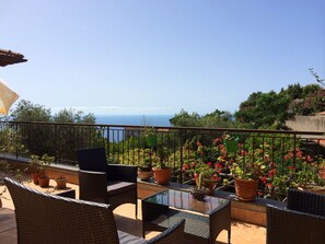 A balcony with wicker furniture, potted plants, and a view of the sea. - Agriturismo Belvedere (Piano di Sorrento)