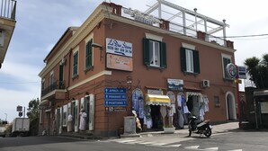 A building with multiple signs indicating directions to nearby locations, a storefront with clothing items, and a sign for a bed and breakfast. - Agriturismo Belvedere (Piano di Sorrento)