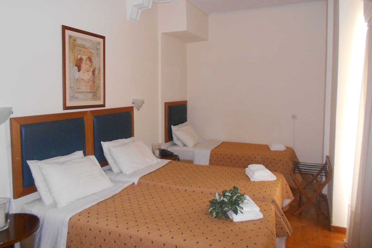 Habitación de hotel con dos camas individuales, una mesita pequeña, una silla y una lámpara fijada a la pared.