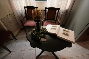 A room with a table, chairs, a book, and a lamp. - Adams Hotel (Athens)