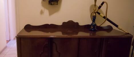 A wooden cabinet with a guitar and hookah on top.
