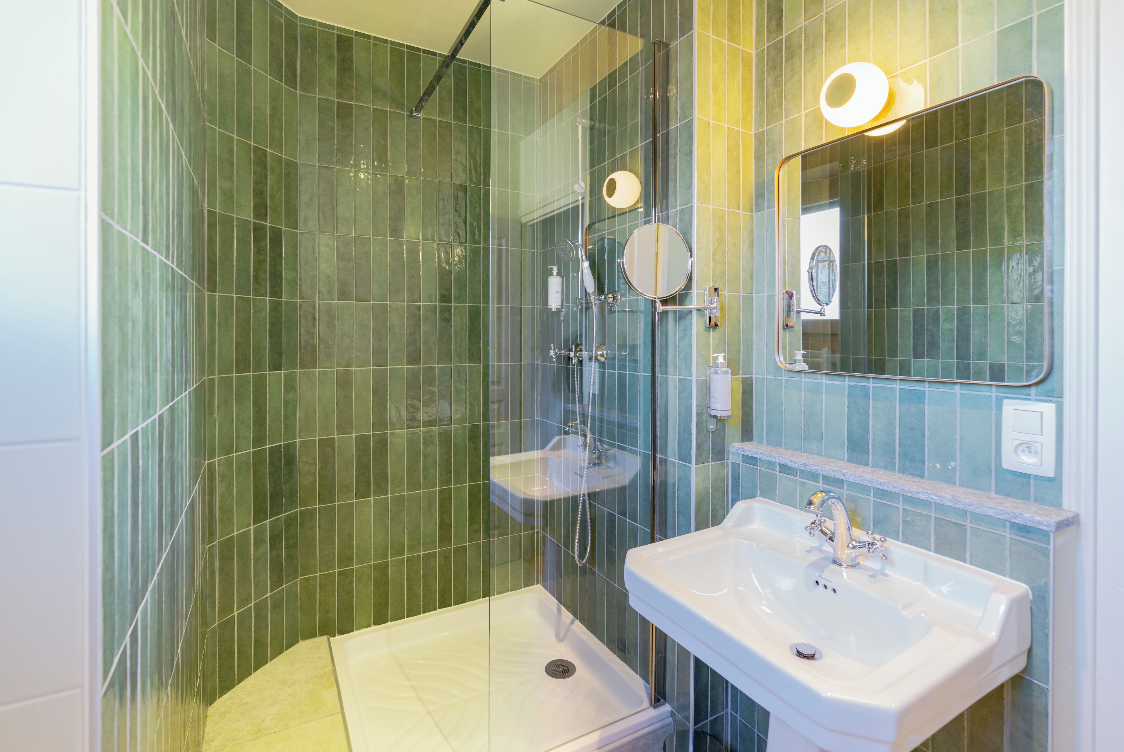A bathroom with a glass-enclosed shower, a sink, and a mirror.