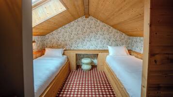 Ein gemütliches Schlafzimmer mit zwei Betten, einem Schachbrettmuster-Boden, Blumenpapier und einem Oberlicht.