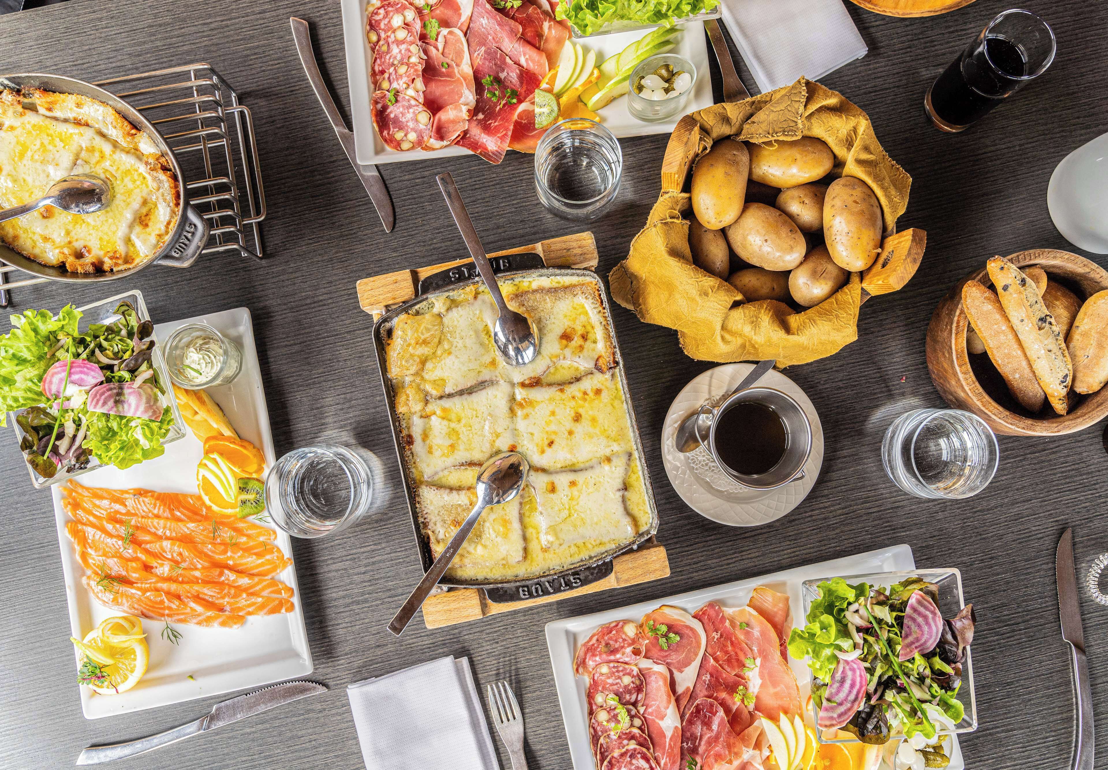 Variedad de alimentos, como salmón, pan y un plato de queso, sobre una mesa.