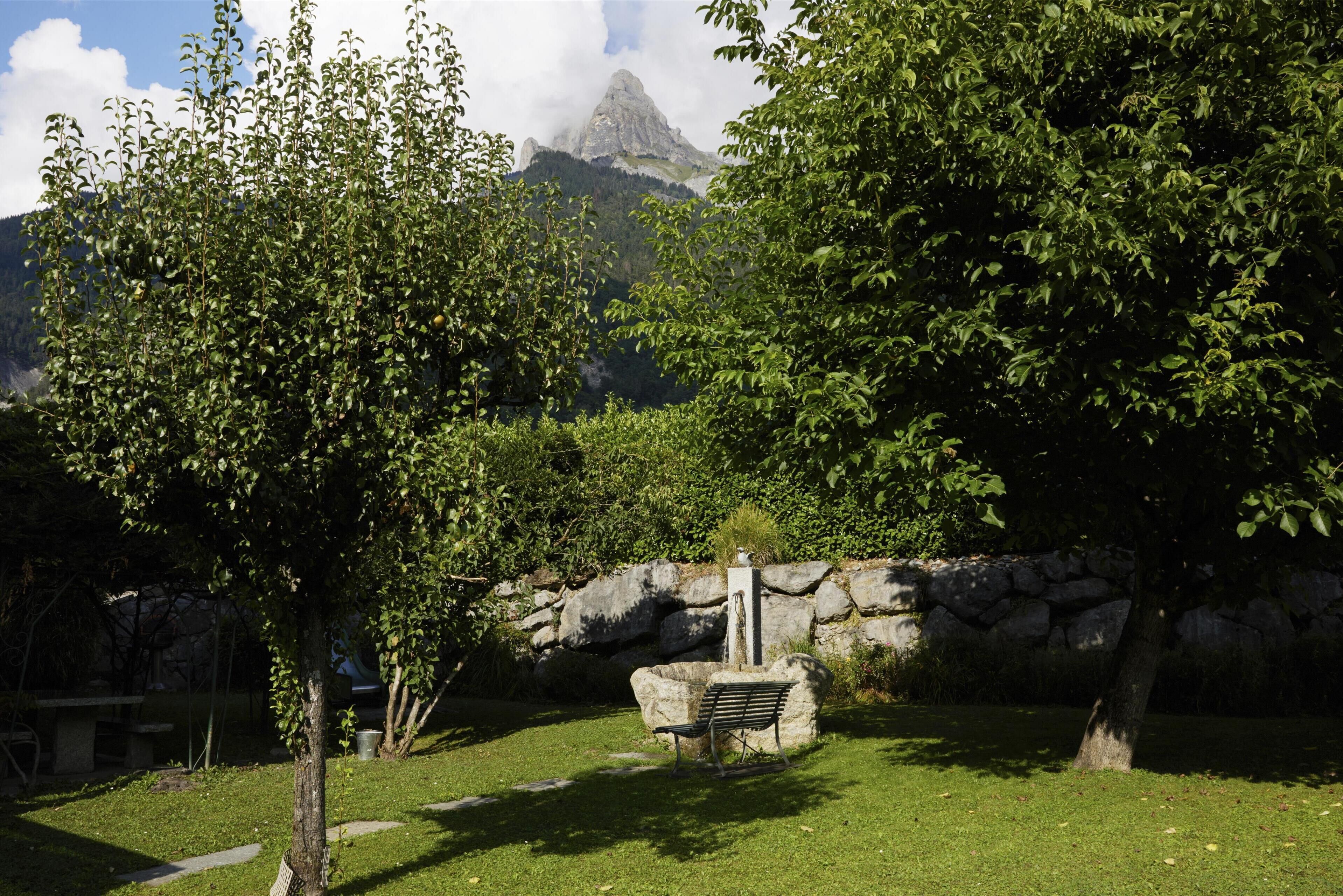 Un parc avec un mur de pierre, un banc et une montagne en arrière-plan.