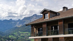 A modern two-story house with a balcony, large windows, and a view of a mountainous landscape. - Best Western Plus Pays du Mont Blanc (Passy)